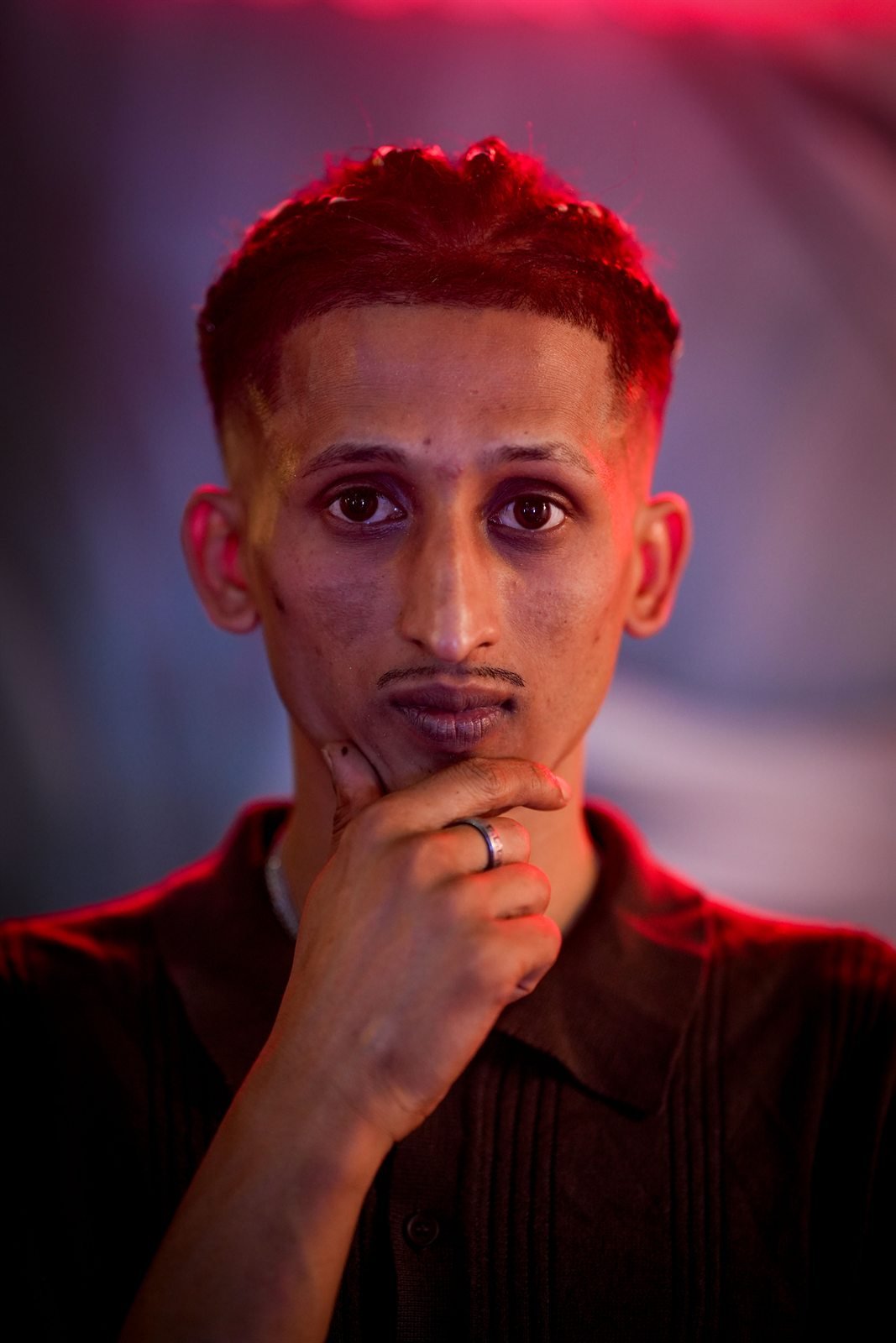 Primo piano di Fida Nadeem con la mano al mento, luce rossa e blu
